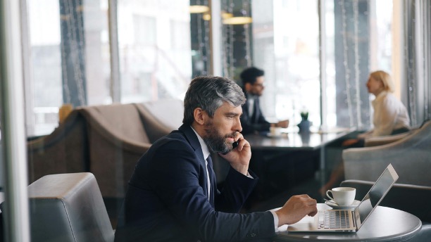 Der arbejdes med desktop og telefon fra en cafe med hjælp fra et mobilabonnement til erhverv